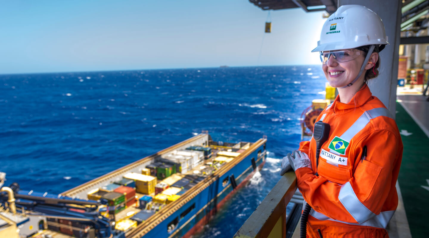 Funcionária com carreira na Petrobras em uma plataforma offshore, usando equipamento de proteção completo.