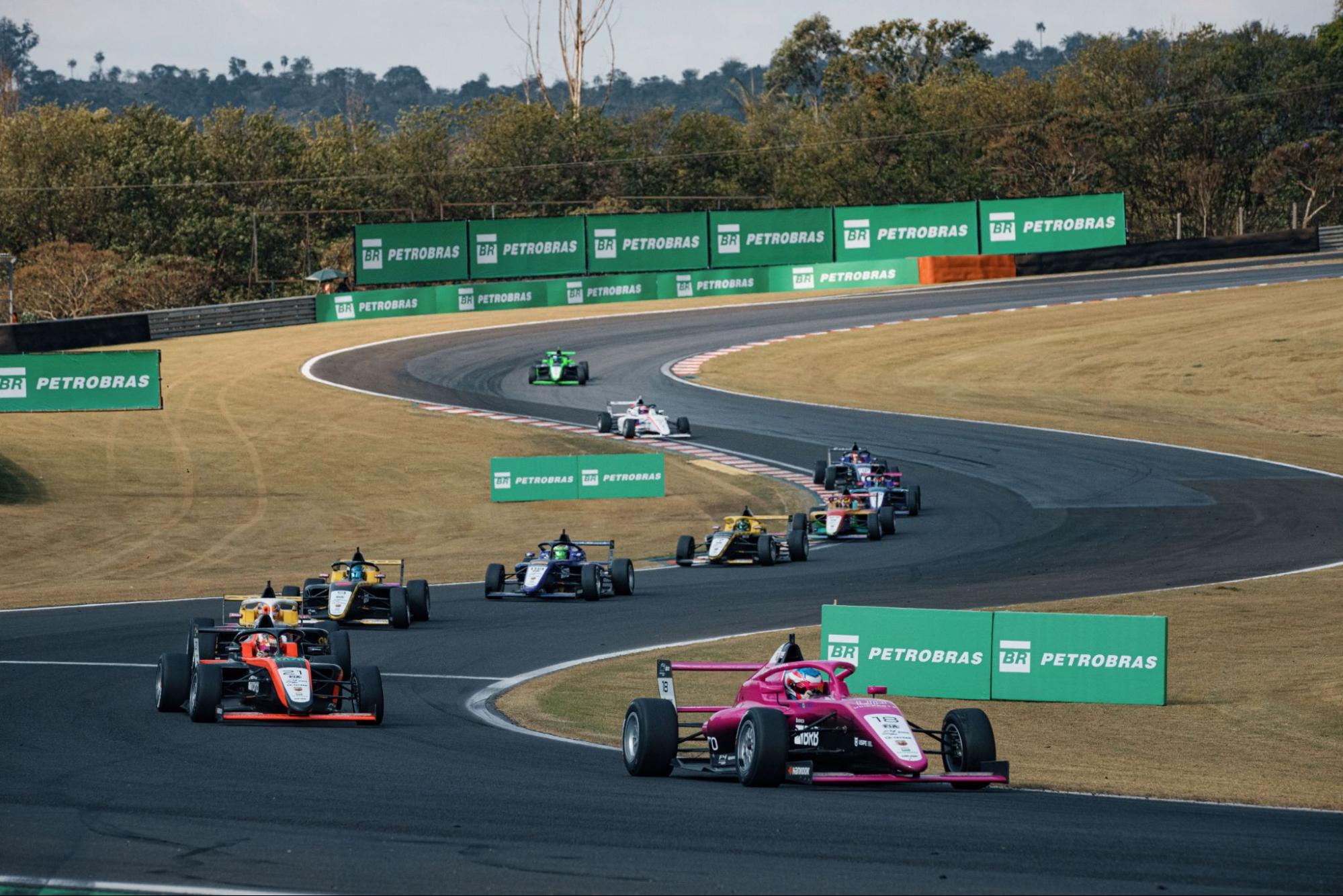 Carros da Fórmula 4 alinhados em um dos 8 circuito com placas do patrocínio Petrobras.