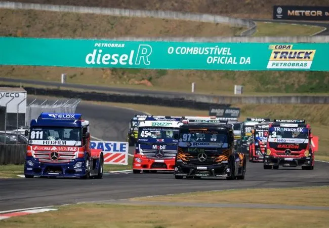 Dois caminhões de corrida da Copa Truck em uma pista, subindo uma colina e levantando poeira, com uma placa de patrocínio verde ao fundo indicando Petrobras Diesel R - O Combustível Oficial da Copa Truck.
