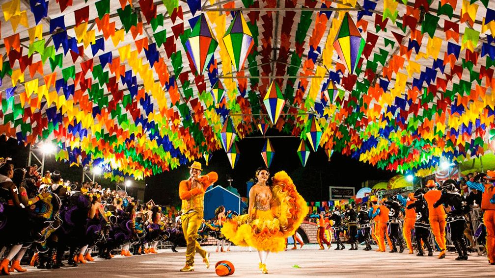 Festa noturna de São João de Caruaru, com bandeirolas e fantasias coloridas.