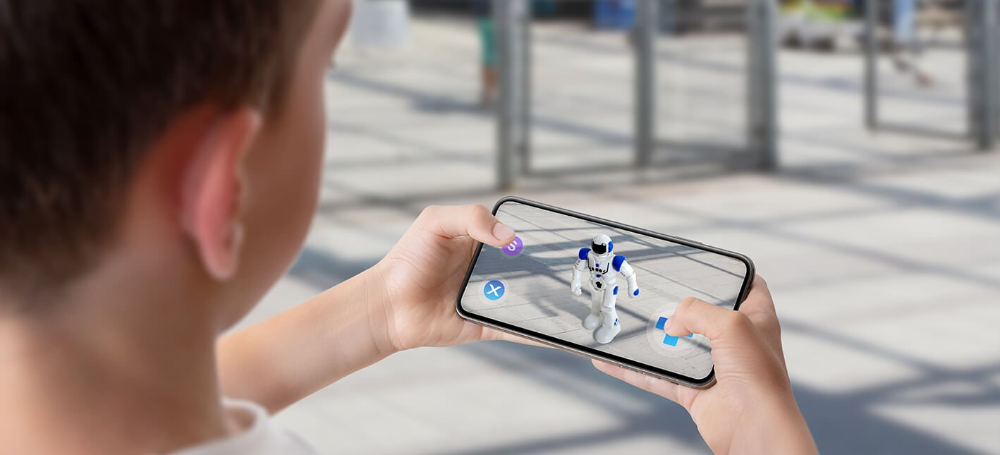 Um menino com celular em mãos, utilizando um aplicativo de realidade aumentada para visualizar um robô em sua frente.