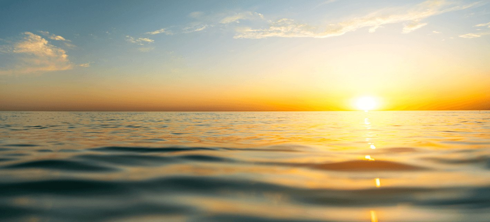 Foto diurna do horizonte entre céu e mar, durante o pôr ou o nascer do Sol.